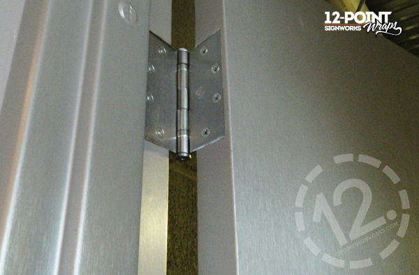 View of the hinge and casing on a door at Black River at Sound Stage. 12-Point SignWorks