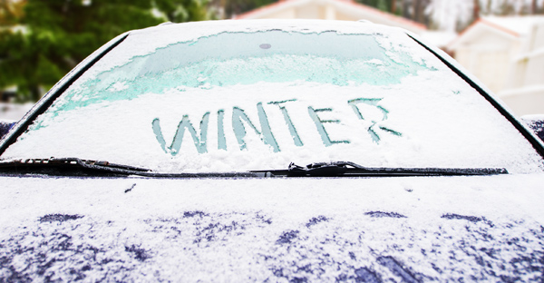 A car covered in snow and ice with 'winter' on the windshield. 12-Point SignWorks