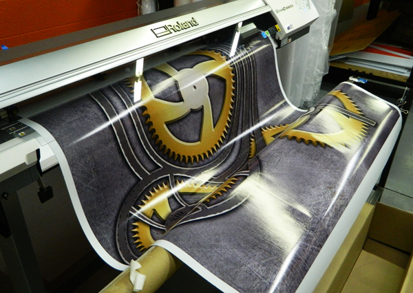 Our Roland printer in action, printing a wrap for a piano. 12-Point SignWorks