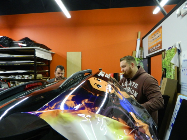 Mike and Rich putting the bumper panel on Janet's Planet Mazda. 12-Point SignWorks