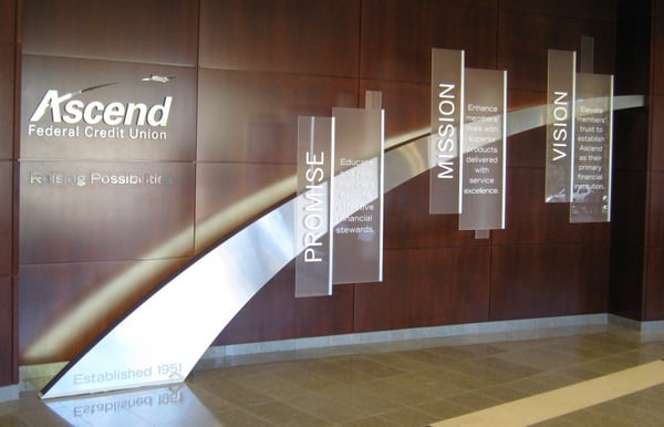 Ascend FCU dimensional brand wall with brushed metal arch, frosted acrylic statement panels and wall-mounted logo sign with brushed and polished metal letters. 12-Point SignWorks