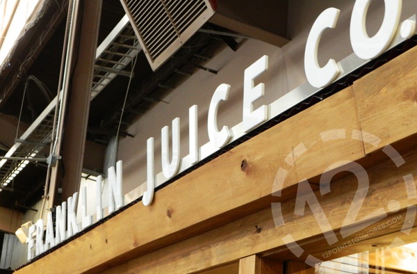 A close-up of the newly installed rail mounted dimensional sign for Franklin Juice Company. 12-Point SignWorks