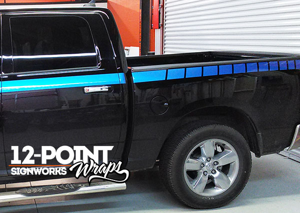 A view of the Mopar style stripes on the bed of a black 2015 Dodge Ram 1500. 12-Point SignWorks