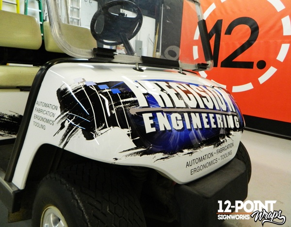 A close-up of the cut vinyl graphics on the front of the Precision Engineering golf cart. 12-Point SignWorks
